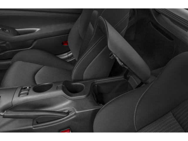 Interior view of a dark gray driver's seat with white stitching and an open armrest revealing a storage compartment.