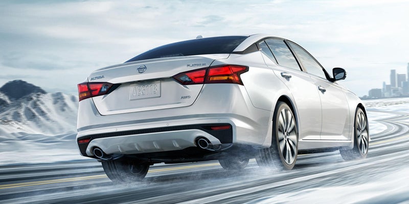 Rear view of a white Nissan Altima driving on a snowy road