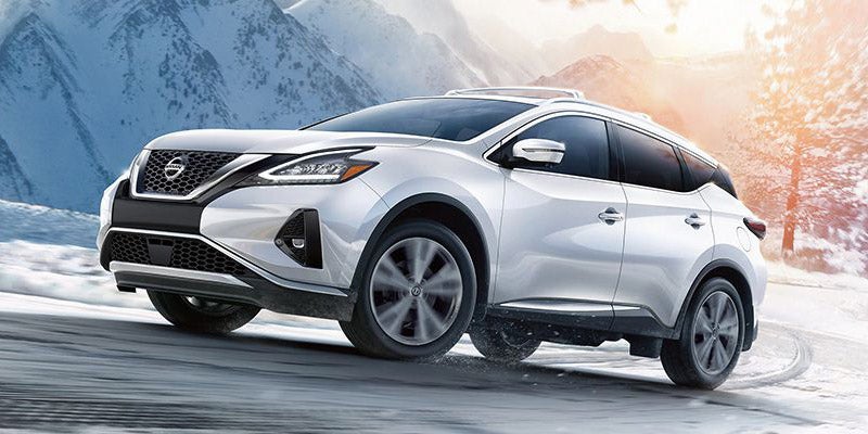 White Nissan SUV driving on a snowy mountain road