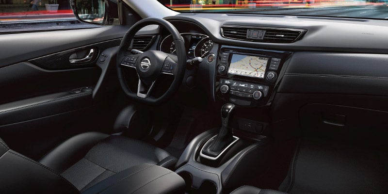 Interior view of a modern car from the driver's seat, showing the dashboard, steering wheel, and front passenger seat