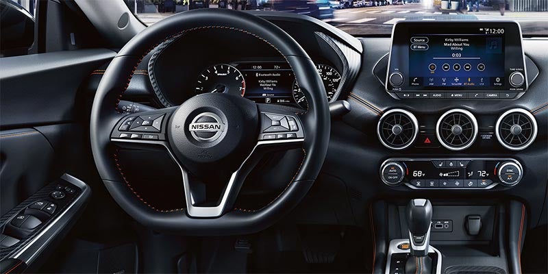 Interior view of a Nissan dashboard focused on the steering wheel, digital gauges