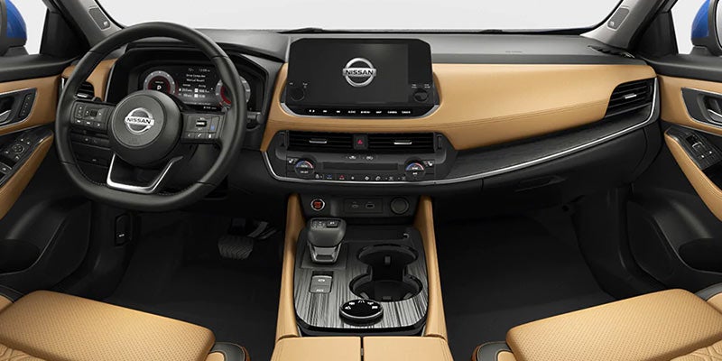 Interior of a Nissan car with tan dashboard and seats, black steering wheel, and a large touchscreen display.