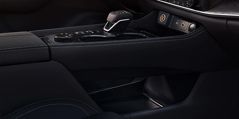 Automotive interior showing the center console, shifter, and charging ports from the passenger's seat perspective