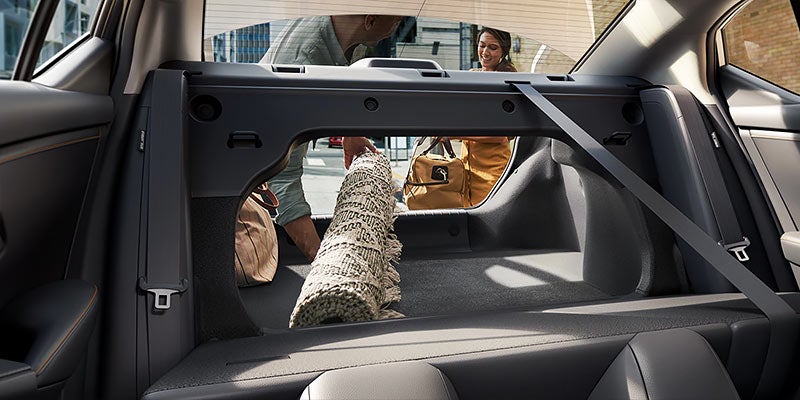 Rear view of a car trunk with an open access panel, luggage