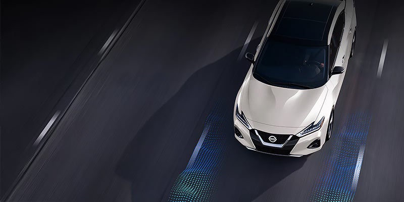 An overhead view of a white car driving on a dark road
