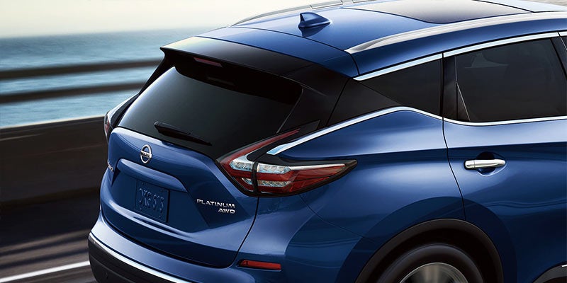 Rear view of a blue Nissan Murano Platinum AWD parked near a body of water.