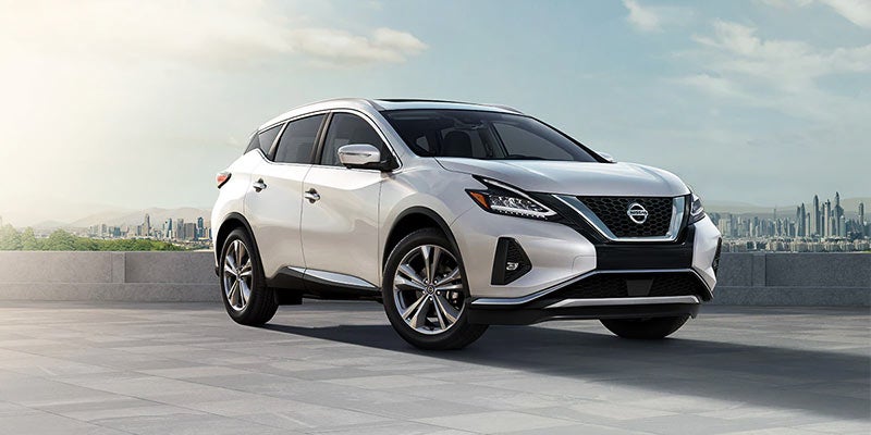 White Nissan Murano SUV on a rooftop parking lot with a city skyline in the background.