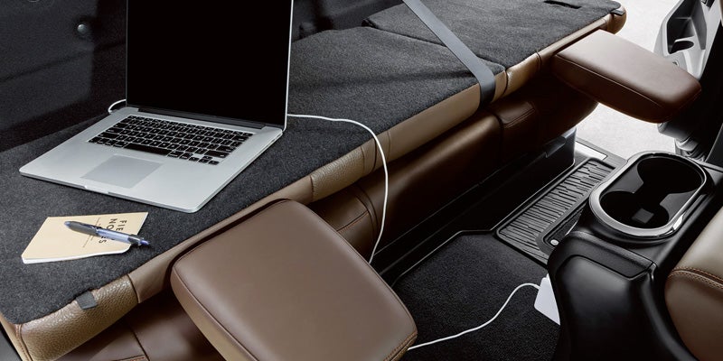 A laptop, notebook, and pen on a car seat converted into a flat workspace