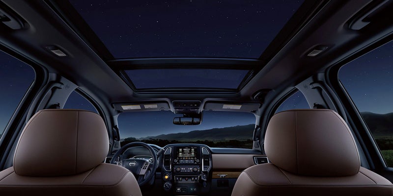 Cabin view from the backseat of a car reveals open sunroof showing a starry night