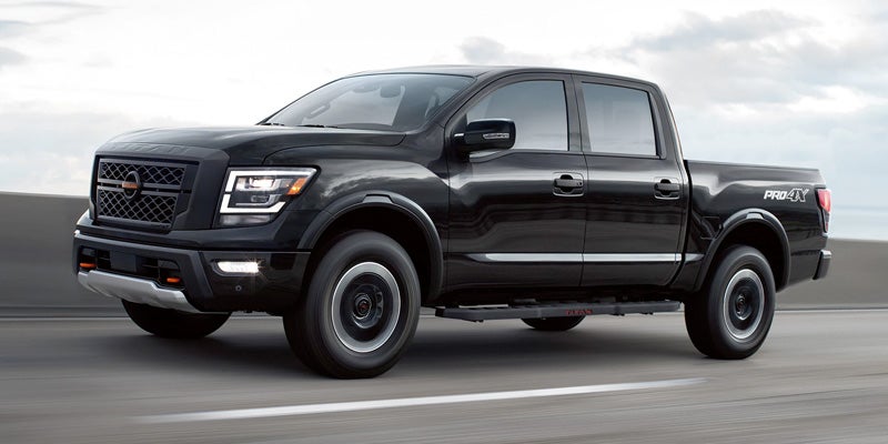 A black Nissan Titan PRO-4X pickup truck driving on a highway.